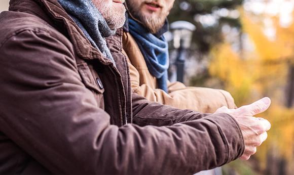 Two men talking while leaning on fence in woods