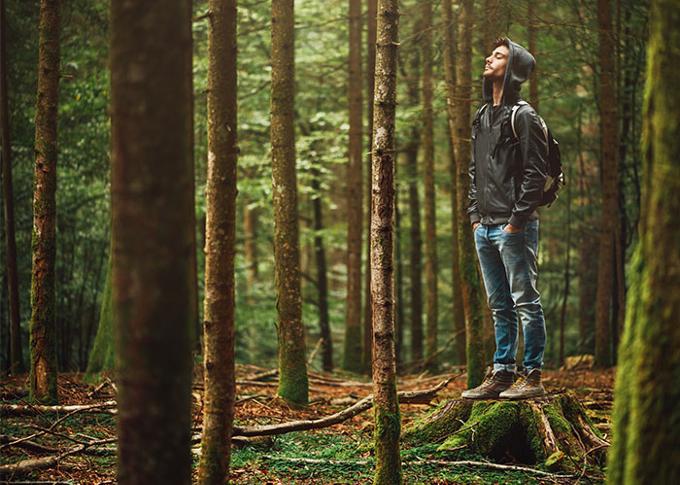 man standing in woods with eyes closed